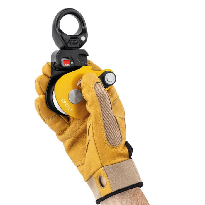 Hand model wearing gloves holding Petzl Spin L1 Pulley showing Triple-action opening of the moving side plate is quick and easy, even with gloves.