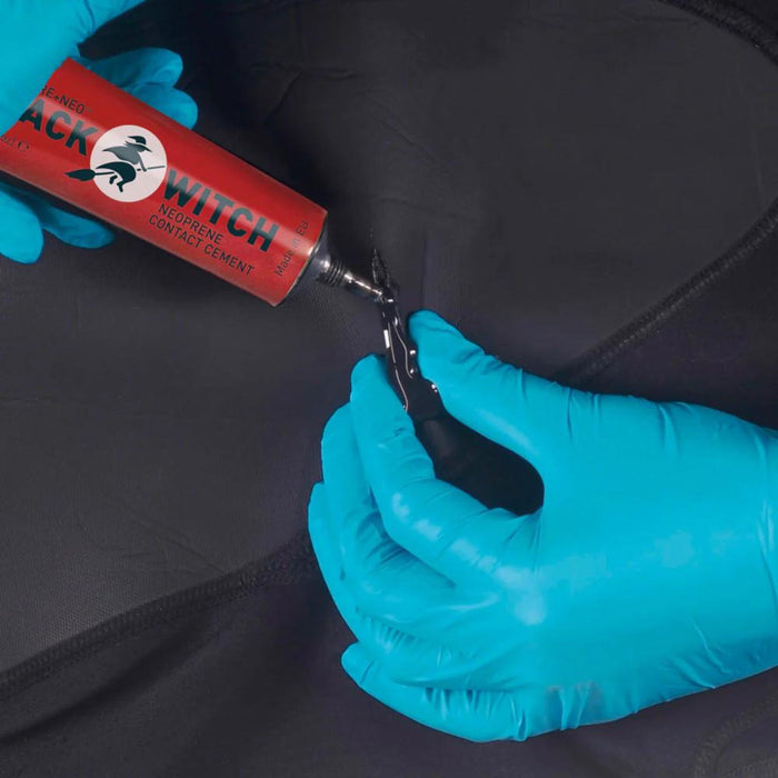 GearAid Black Witch Aquasure Neoprene Adhesive being applied to a neoprene black tear by model wearing blue plastic protective gloves 