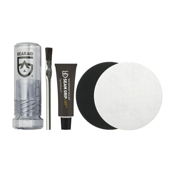 Gear Aid Seam Grip Field Repair Kit Content items laid out on a white background. These items are : Gear Aid Kit Storage Container, an Applicator Brush, 7g Tube of Waterproof Sealant Seam Grip +WP, 7.62 cm Waterproof Black Tenacious Tape Patch and 7.62 cm Waterproof Clear Tenacious Tape Patch