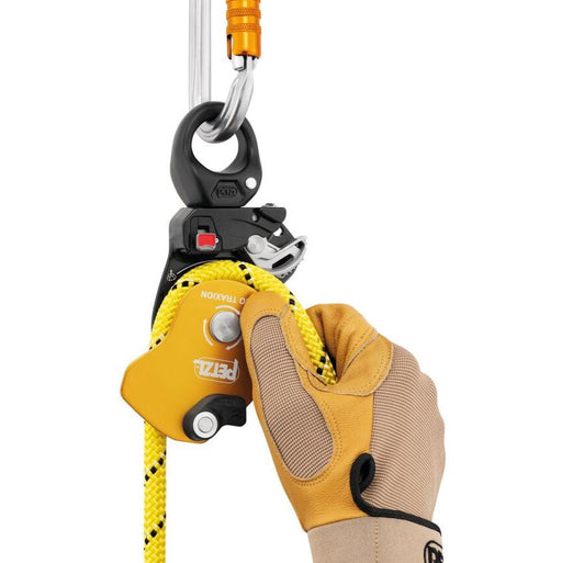 Professional wearing gloves installing a rope on the Petzl Pro Traxion pulley when the pulley is connected to the
anchor.