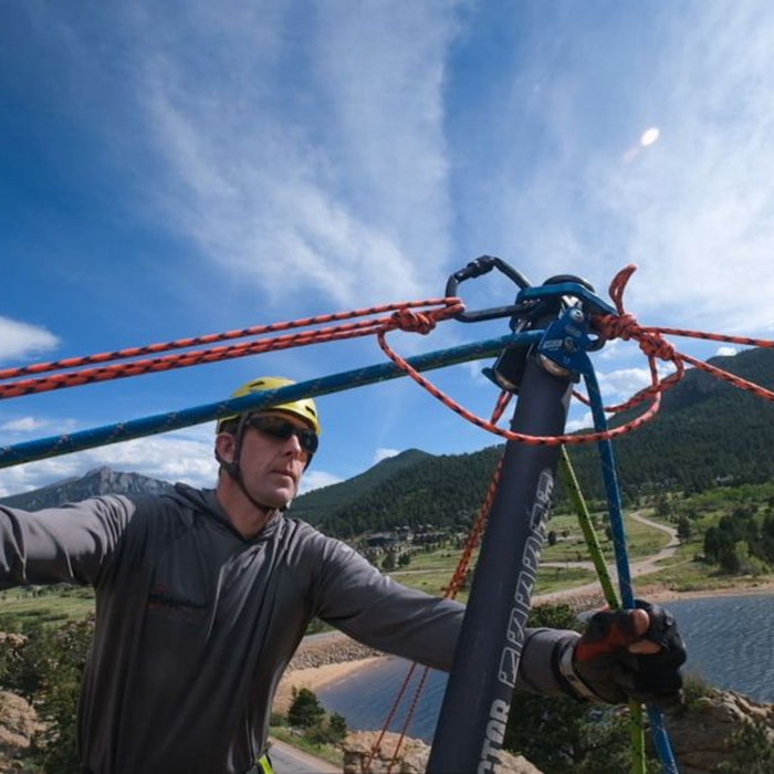 Rescuer using the SMC Vector Edge and Load Management System with multiple rigged ropes. SMC Apex 1.1 Pulleys are attached for load control and directional support in an outdoor rescue environment.